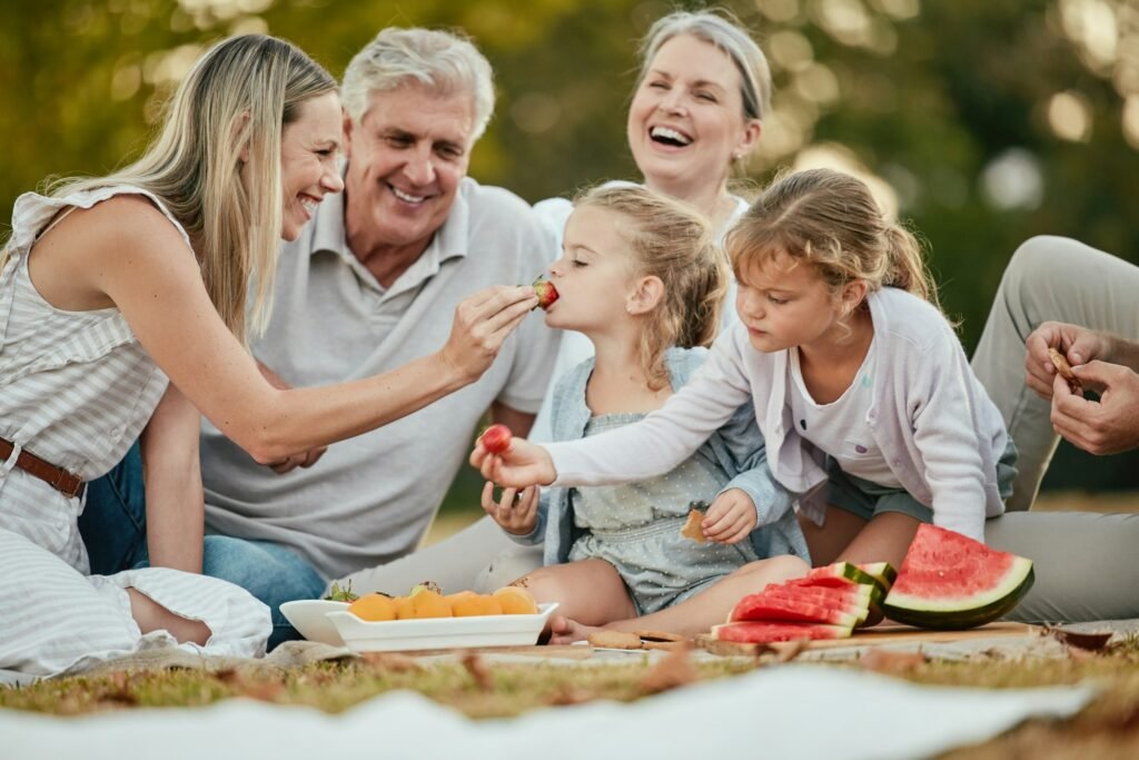 Summer, park and family on picnic with fruit enjoying summer holiday, vacation and weekend together